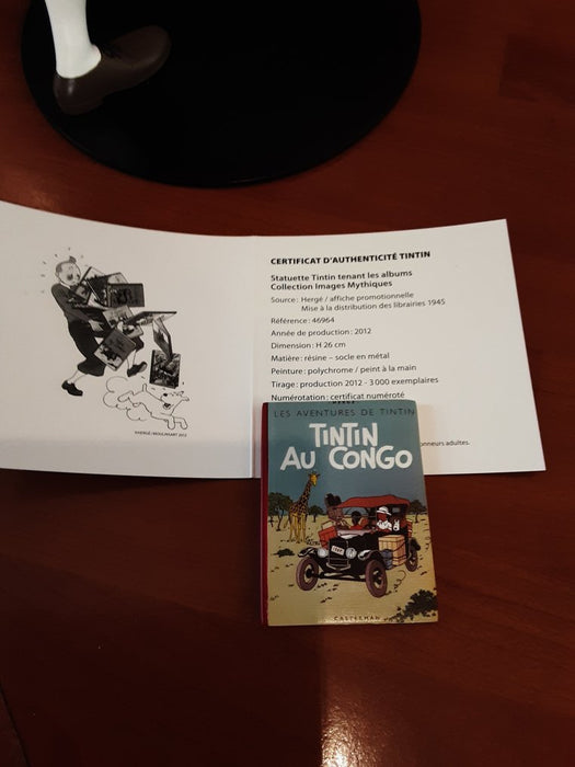Tintin tenant ses albums, Milou à ses côtés